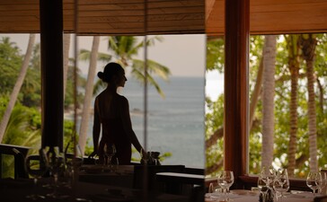 Persona che cena presso il ristorante Arva ad Amanpuri, resort in Tailandia, con vista sul mare.