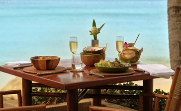 Tavolo sulla terrazza spiaggia di Amanpuri con bicchieri e champagne, vista sul mare.