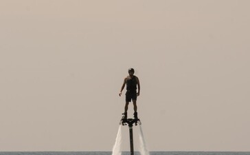 アマンプリ・リゾートでフライボードを体験する人物、海の上で水しぶきを上げている。