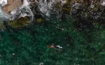 浮潜者在安缦璞瑞度假村清澈的泰国海水中潜水，俯视图。