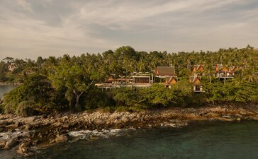 Aerial view of Amanpuri villa nestled amongst tropical gardens on Thailand's coastline.