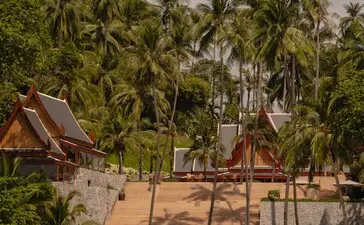 安缦璞瑞度假村的海滩楼梯，背景为棕榈树和泰国传统建筑。