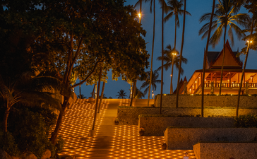 アマンプリ リゾートの夕暮れ時、照明に照らされたテラスと椰子の木。