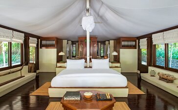 Oceanfront principal bedroom at Amanwana with cream-coloured furnishings, wooden accents, and large windows overlooking the sea.