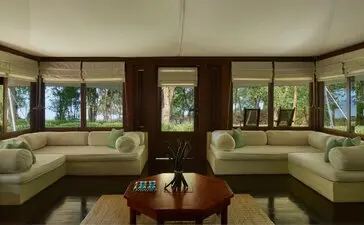 Amanwana jungle tent living area with curved seating arrangement and floor-to-ceiling windows overlooking tropical forest.