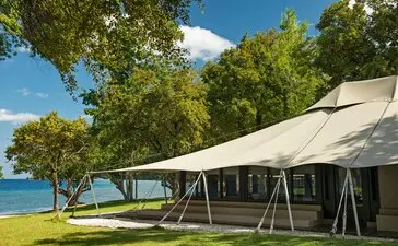 Oceanfront canvas tent at Amanwana, Indonesia, with open sides and ocean views beyond green lawns.