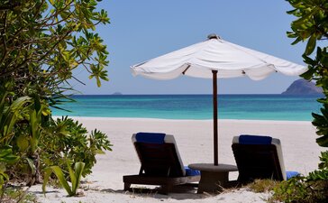 Duas espreguiçadeiras e um guarda-sol na praia de Amanpulo, resort nas Filipinas.