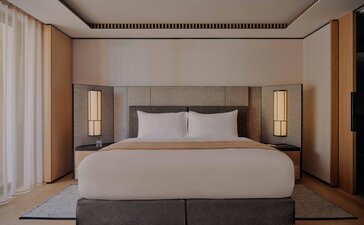Deluxe room at Aman Rosa Alpina resort with queen bed, warm wooden panelling and soft lighting.