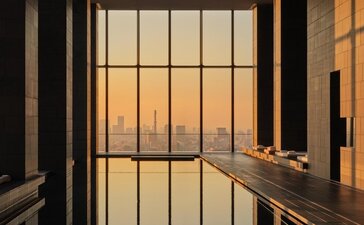 Aman Tokyo hotel spa pool with grid-lined windows overlooking city at dusk.