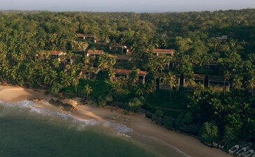 Aerial view of Amanwella's beachfront suites set amongst dense tropical forest along a quiet sandy cove.
