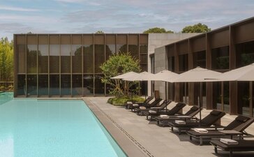 Amanyangyun spa pool surrounded by loungers and dark wooden pavilions in China.