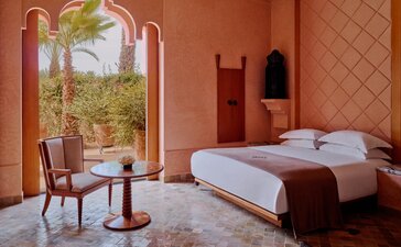 安缦珍纳度假村双卧室泳池别墅卧室，配有露台景致、赤土色墙壁和现代床铺。