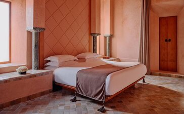 Grand Two-Bedroom Pool Villa principal bedroom at Amanjena resort, Morocco, with terracotta walls and twin beds.