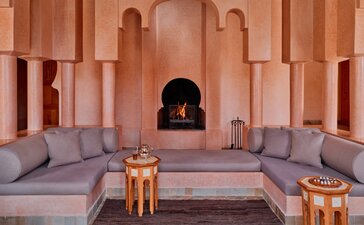 安缦珍纳度假村的双卧室泳池别墅内部，设有对称的灰色座椅、拱形壁龛和摩洛哥风格建筑。