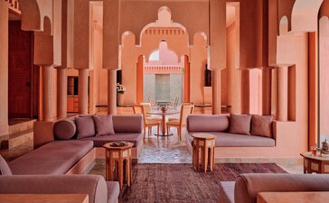 安缦珍纳度假村宽敞的两卧室泳池别墅内部，展示对称的拱形走廊和摩洛哥建筑风格。