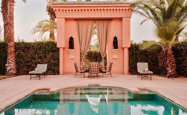 安缦珍纳度假村的两卧室泳池别墅，粉红建筑前有清澈的水池。
