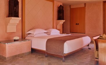 Principal bedroom at Amanjena resort, Morocco, with terracotta walls and two beds.