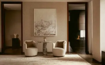 Zona living della penthouse a tre camere di Aman New York, con poltroncine in tonalità neutre e opere d'arte alle pareti.