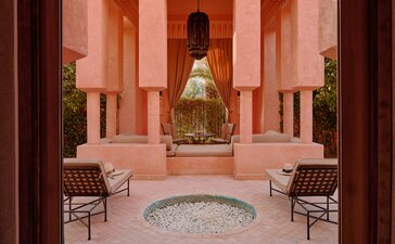 安缦珍纳度假村的粉红色拱廊亭阁，中央是圆形水池，两侧摆放座椅。