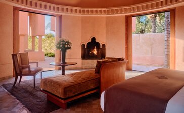 Pool pavilion lounge at Amanjena in Morocco with terracotta walls and wooden furnishings.