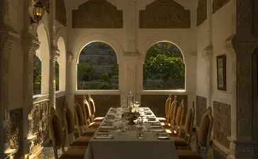 安缦丘澜度假村皇家晚宴餐厅，白色拱廊两侧摆放餐桌，绿色植物点缀其间。