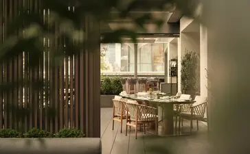 Terraço de jardim com entrada de madeira escura, mesas de jantar e cadeiras ao fundo no Aman New York.