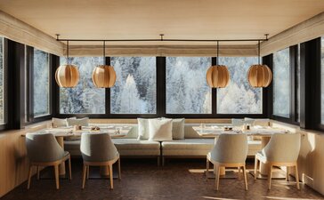 Heritage Room at Aman Rosa Alpina with curved seating, abstract artwork, and warm lighting.