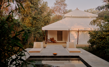 Tented pool pavilion at Aman-i-Khas in India, with warm lighting at dusk and surrounding vegetation.