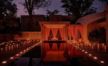 Private pool pavilion candlelit dinner at Amanbagh, India, at dusk.