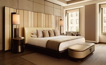 Camera da letto con letto matrimoniale e pouf beige in una suite d'angolo presso Aman New York.