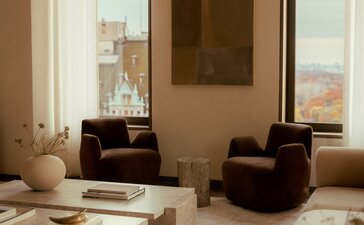 Penthouse living area at Aman New York with floor-to-ceiling windows, neutral furnishings and city views.