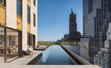 Terrace with reflecting pool overlooking Manhattan skyline at Aman New York hotel.