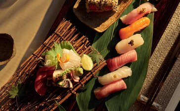 アマン ニューヨークのダイニング会場で、緑の皿に盛り付けられた寿司と刺身の盛り合わせ。