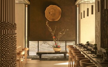 アマン ニューヨークのホテルロビー。天井から吊るされた大きな円形のオブジェと、奥に広がる落ち着いた空間。