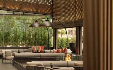 Terazza giardino lounge presso Aman New York, con sedute in vimini e veduta sul giardino.
