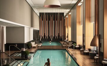 Piscina coperta con vasca rettangolare presso Aman New York, hotel con pareti chiare e illuminazione naturale.
