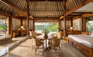 Amandari one-bedroom villa bedroom interior with thatched ceiling, wooden furnishings, and garden views.