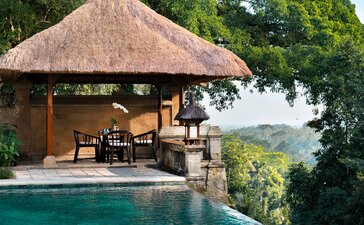 Open-air dining bale at Amandari with thatched roof, overlooking Balinese landscape and plunge pool.