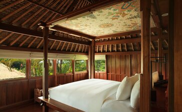 Bedroom in a duplex pavilion at Amandari, Indonesia, with a four-poster bed and wooden ceiling detail overlooking tropical gardens.