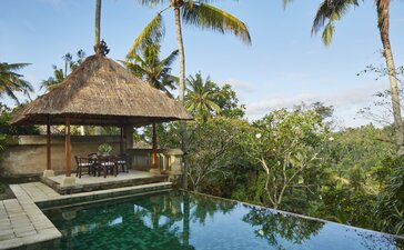 Garden pool pavilion at Amandari with thatched-roof bale overlooking reflective water and tropical vegetation.