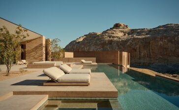 アマンギリのシックス・ベッドルーム・ヴィラのプール・テラス。砂漠の崖を背景に、静寂に満ちた水面が広がる。