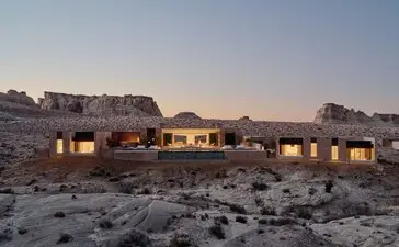 アマンギリのリゾートに位置する、砂漠の夕暮れ時に灯りが灯った六室ヴィラの外観。