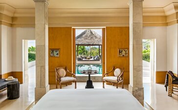Garden Suite bedroom at Amanjiwo with pool pavilion view through open doors, Indonesia.