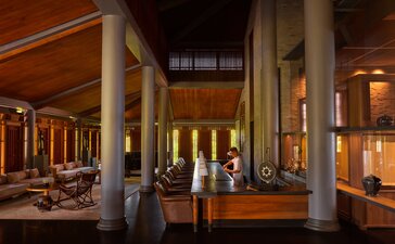 Bar at Amanoi with wooden interior, supporting columns and warm ambient lighting.