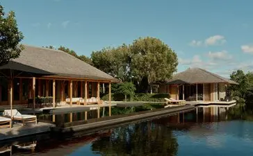 Amanyara villa with pool overlooking calm water, framed by tropical greenery under clear sky.