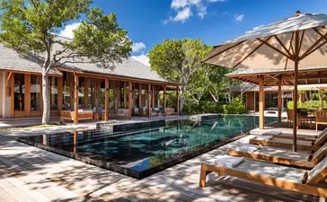 Amanyara four-bedroom beach villa with infinity pool, thatched pavilions, and sandy courtyard in Turks and Caicos.