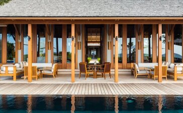 Four-bedroom ocean villa pavilion at Amanyara with wooden columns and deck overlooking turquoise waters.