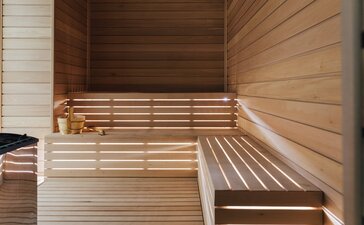 Sauna in legno presso il resort Amanzoe in Grecia, con panche in legno chiaro e pareti rivestite.