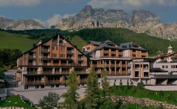 Aman Rosa Alpina resort exterior with traditional Alpine architecture set against mountain peaks in Italy.