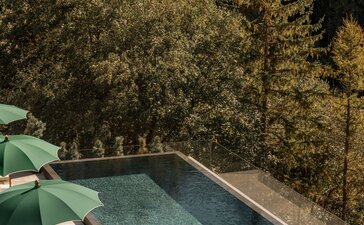 Outdoor swimming pool at Aman Rosa Alpina resort overlooking forested Italian Alps, with loungers and green umbrellas beside the water.